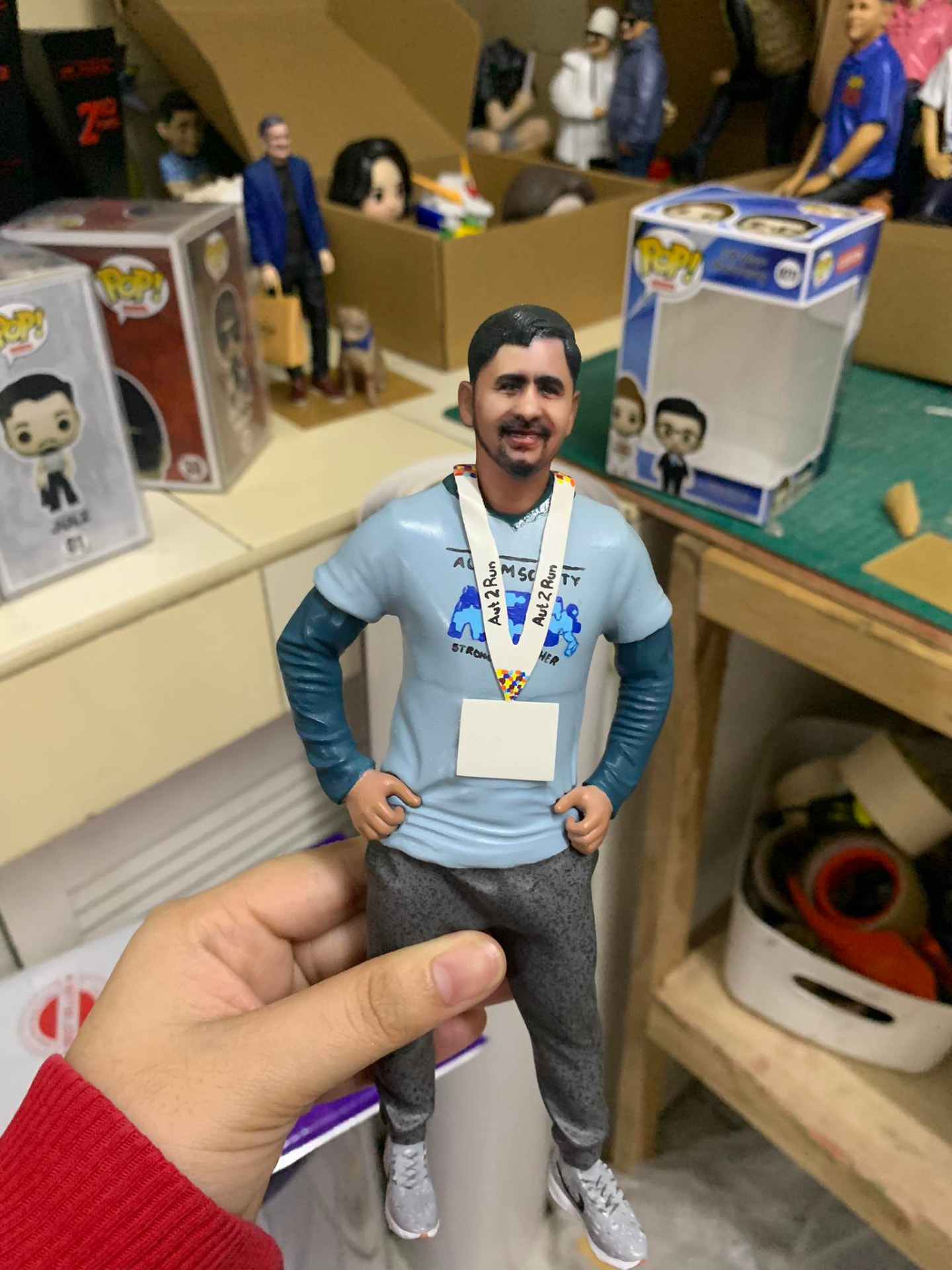Full-color 3D printed figurine of a man in a blue shirt with a race medal, held in a hand