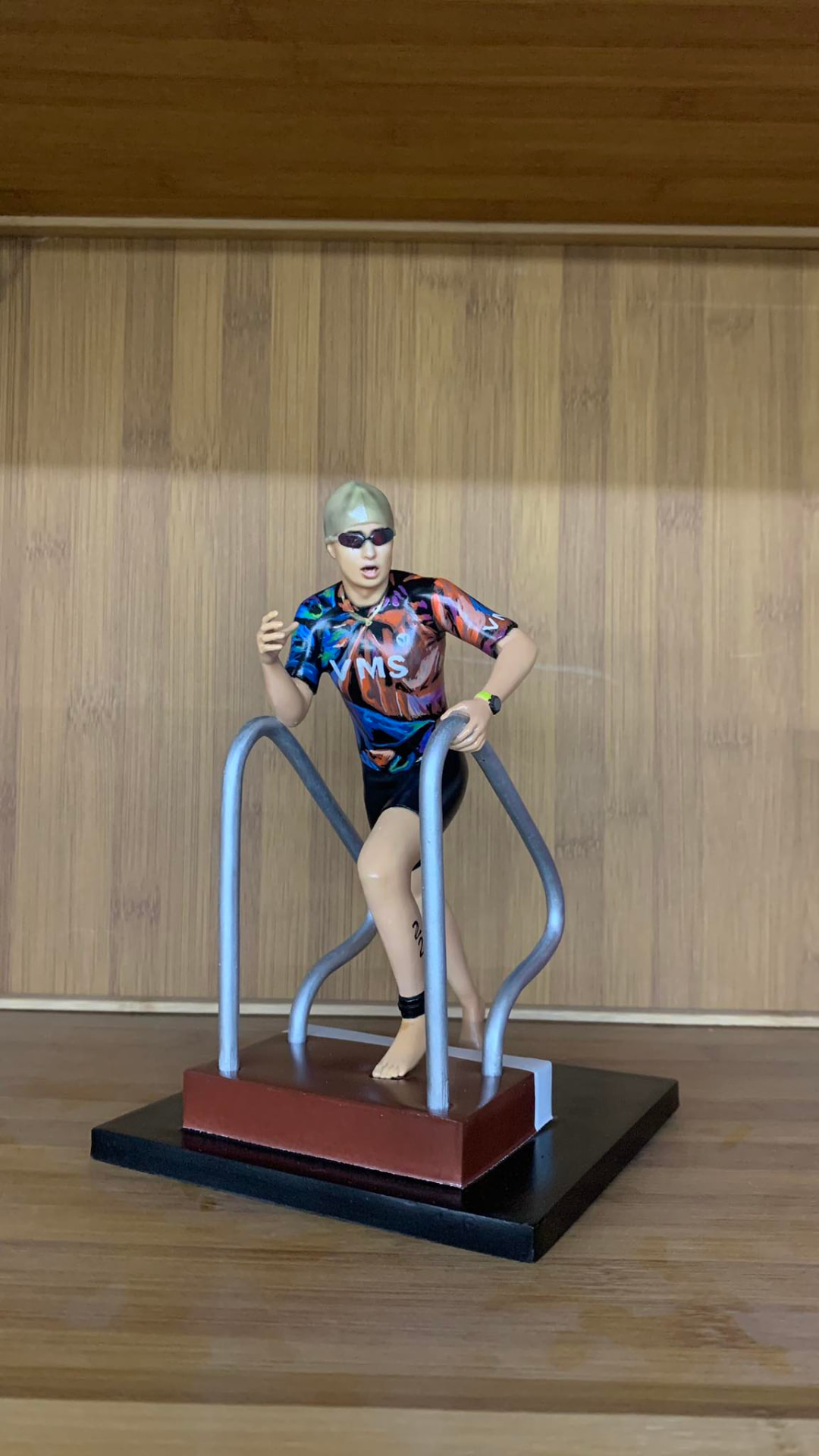 Full-color 3D printed figurine of a triathlete in a swim cap and racing suit on a display base